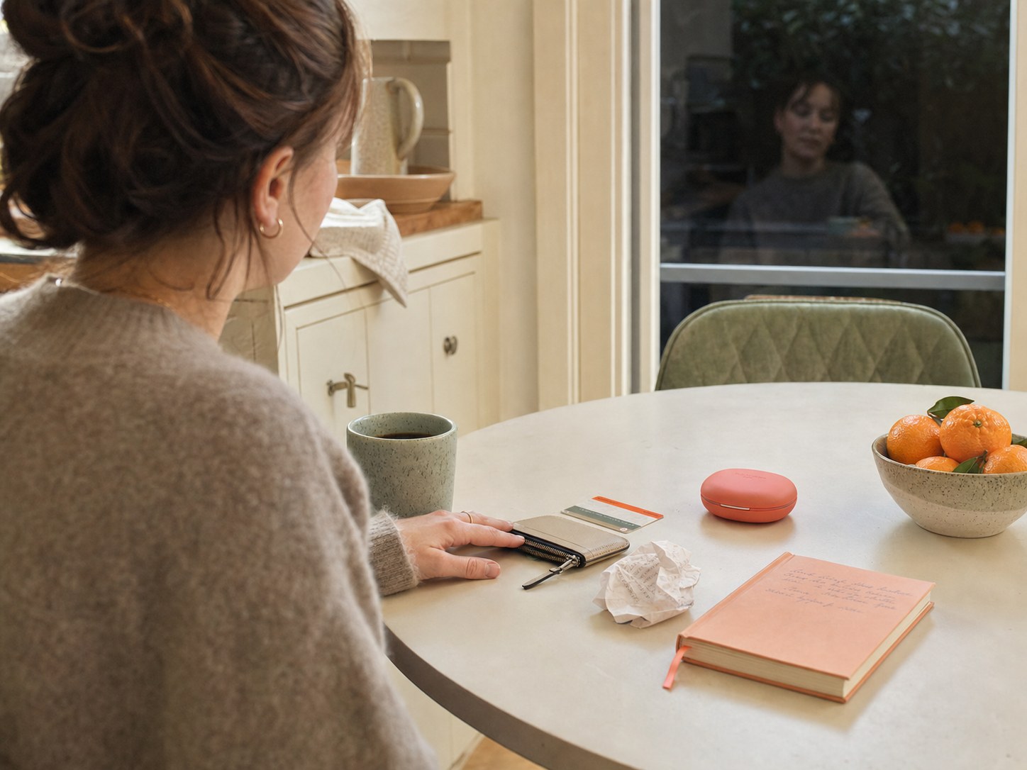 Una mujer revisa lo que necesita para el día en una mesa de cocina, junto a un pequeño estuche coral para alineadores.