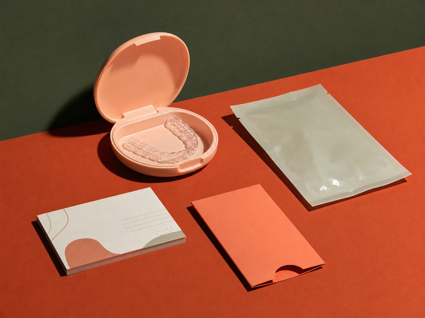 Un estuche color melocotón para alineadores, una pequeña férula transparente, una funda para retenedores y varias tarjetas de cuidados forman un kit de tratamiento completo.